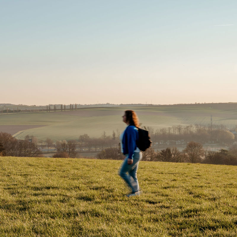 Meisje met rugzak wandelt alleen op panoramaplek in zuid-limburg.