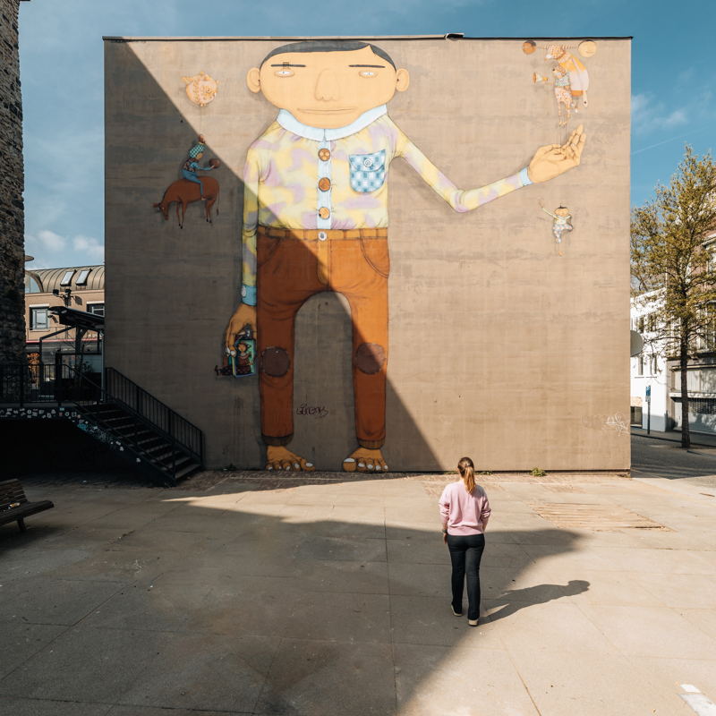 Mural van grote reus met een kleine persoon die ernaar kijkt