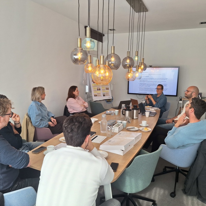 Meerdere personen zitten aan een tafel tijdens een brainstormsessie over AI.