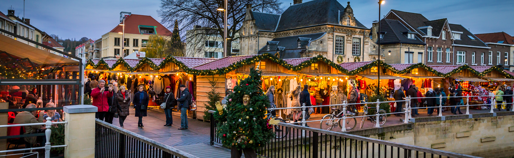 Man in kerstboompak op brug voor kerstkraampjes