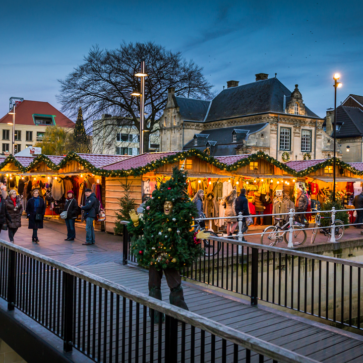 Man in kerstboompak op brug voor kerstkraampjes