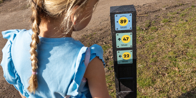 Meisje bekijkt knooppuntenpaal van dichtbij.