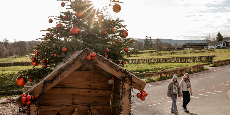 Twee dames lopen langs een kerststal in het heuvelland.
