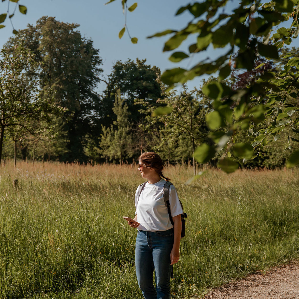 Vrouw is alleen aan het wandelen in een weiland omgeven door bomen