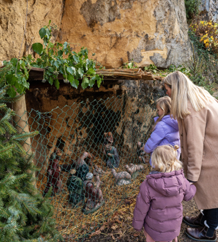 Moeder en dochter kijkend naar Kerstkribke in grot