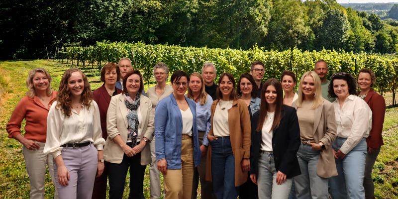 Groepsfoto van alle partners van de wijnstraat voor een groene wijngaard