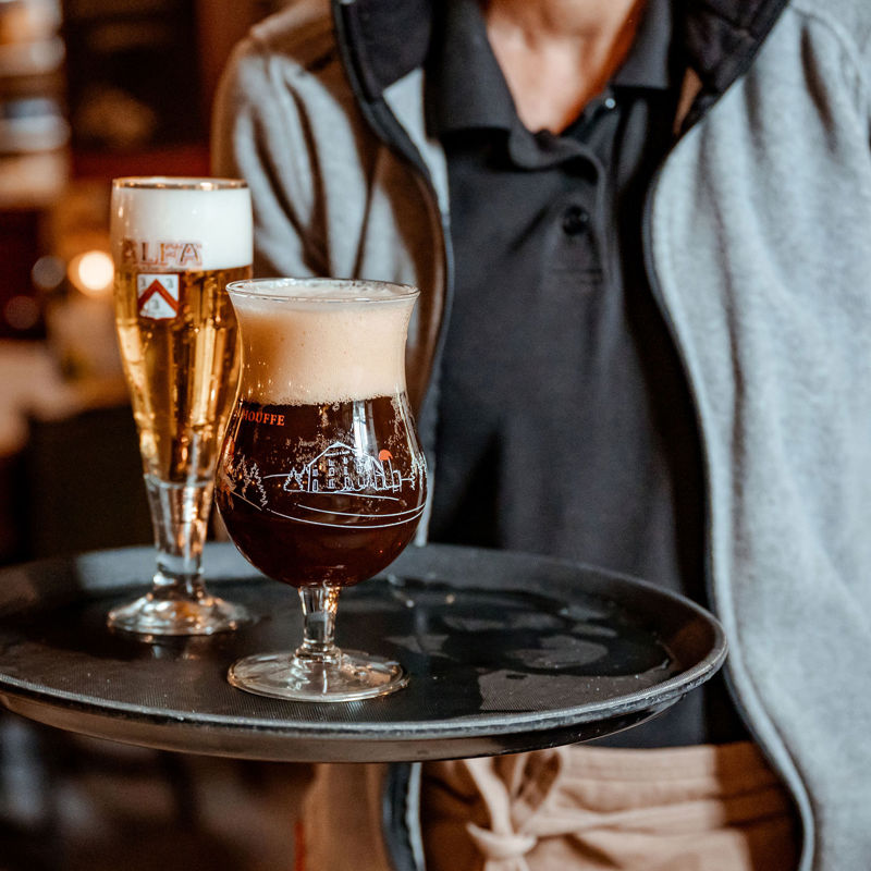 Horecamedewerker houdt dienblad vast met daarop twee lokale biertjes van de tap.