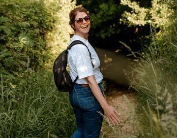 Een lachende vrouw draait zich halverwege om en lacht, terwijl ze wandelt door de mooie natuur